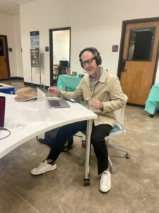 White man wearing glasses, using a laptop and headphones in the DH Center 