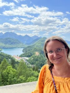 Woman in a yellow shirt in front of view of lake and mountains