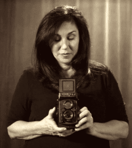 Woman holding a camera before a grey background