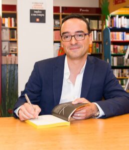 Man in a blue suit signing a book